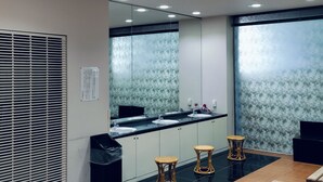 A modern bathroom with a large mirror, two sinks, and three stools.