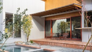 Ein modernes Haus mit Pool, Sitzgelegenheiten im Freien und einer Pergola.