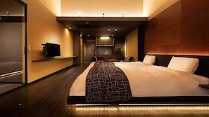 Et moderne hotelværelse med en stor seng, et fladskærms-tv, en minibar og et badeværelse med bruser og toilet.