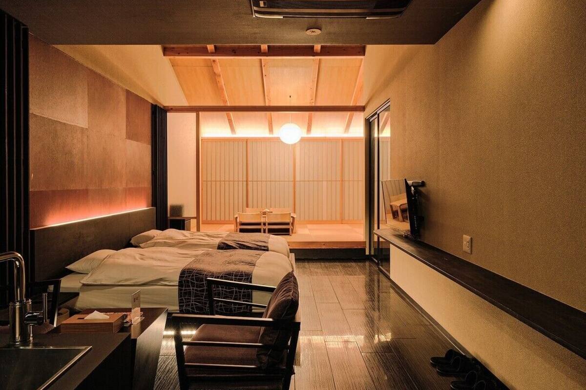 Una habitación de hotel con cama, escritorio, silla, televisor y baño.