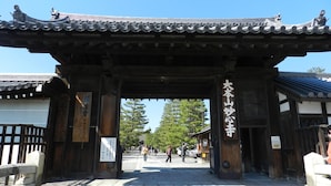 Un portón japonés tradicional con pilares de madera y techo de tejas.