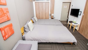 Una habitación de hotel con dos camas, televisión, escritorio con silla y armario.