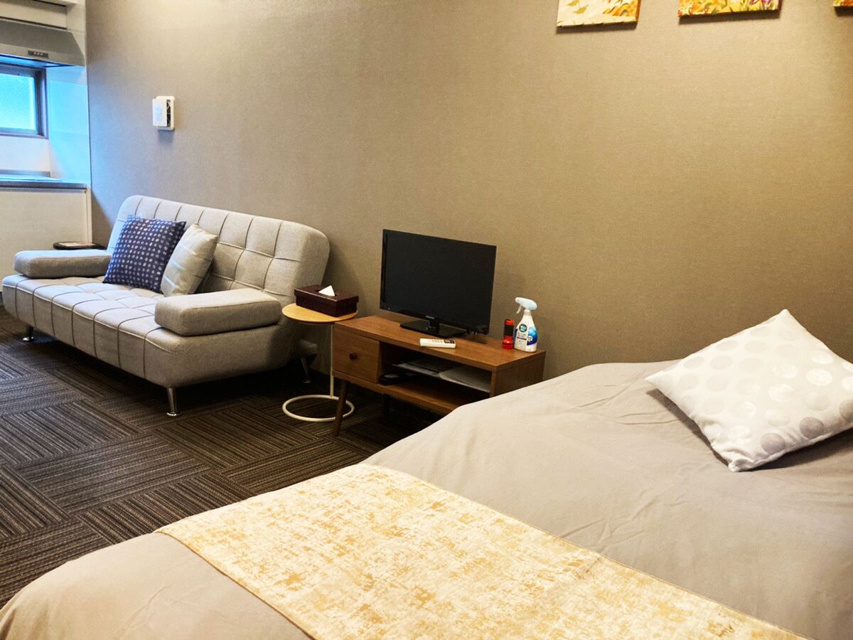 A hotel room with a bed, a sofa, a TV, and a desk.