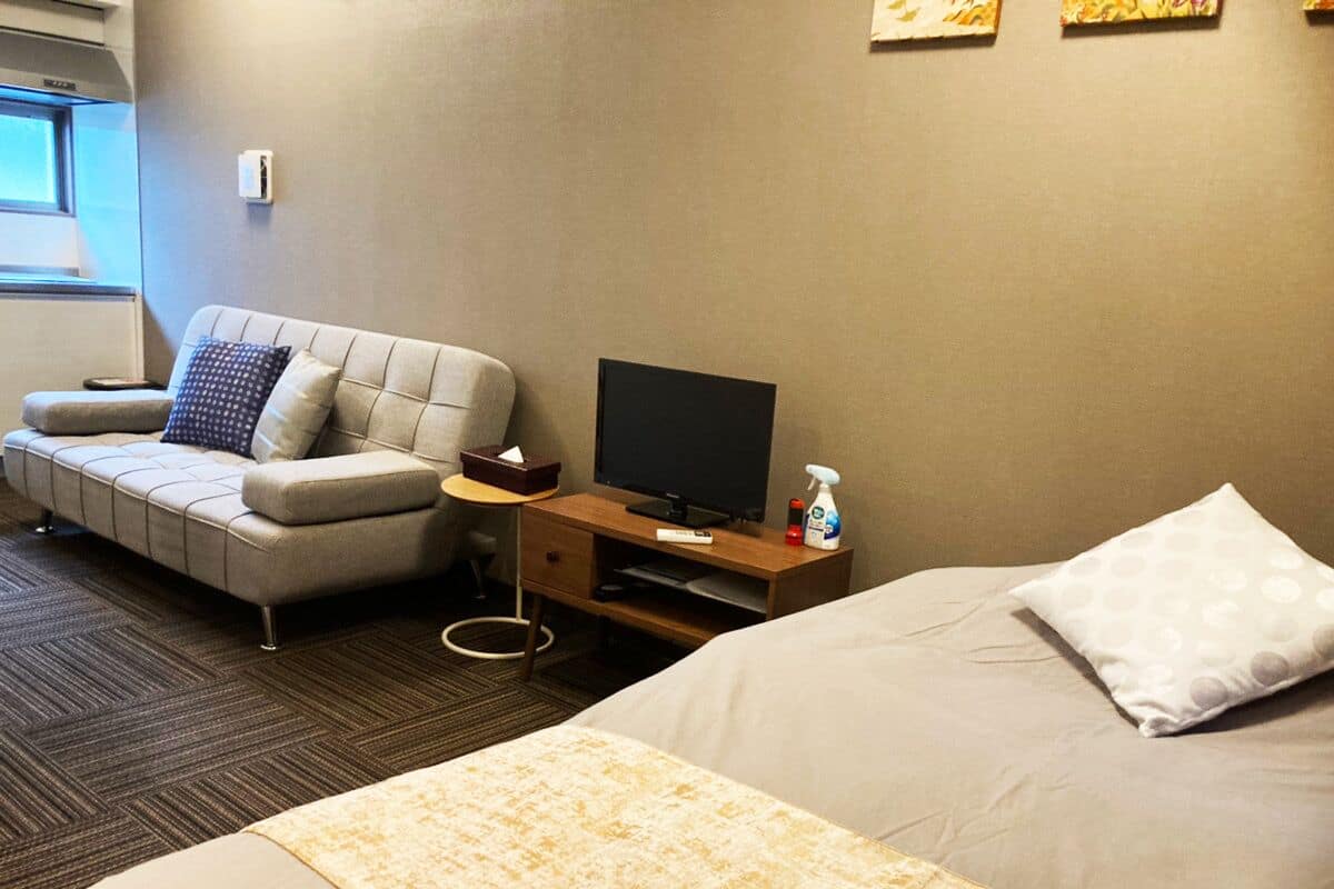 Ett hotellrum med en säng, en soffa, en tv och ett skrivbord.