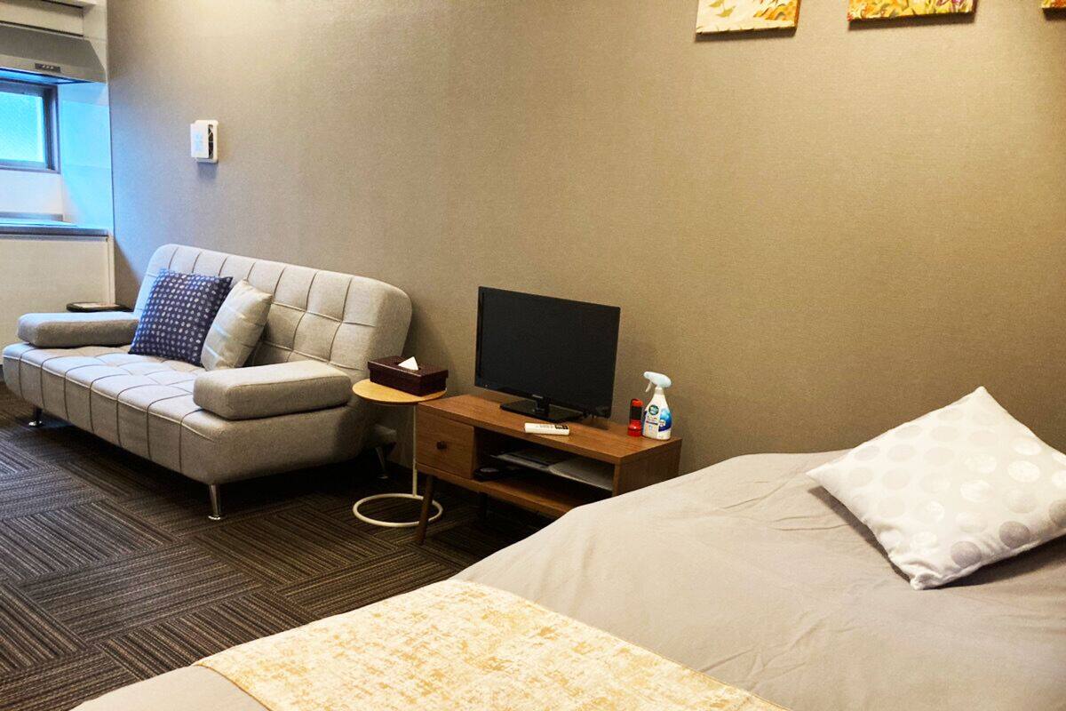 Una habitación de hotel con cama, sofá, televisión y escritorio.