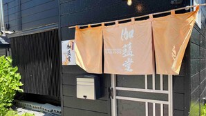 A building with a dark exterior, a window with a decorative pattern, and a signboard. - Garando (Hakodate)