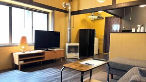 A modern living room with a flat-screen TV, a heater, a refrigerator, and a sofa. - Garando (Hakodate)