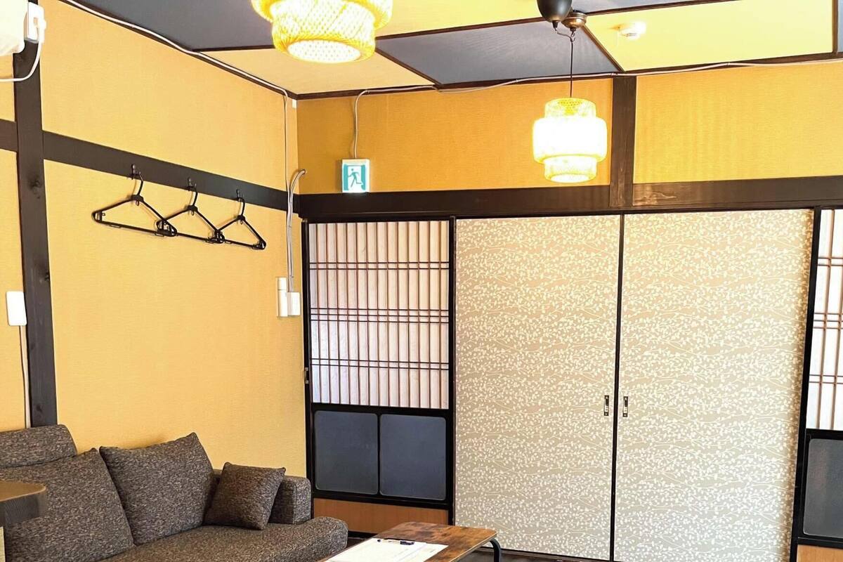 Una habitación con sofá, mesa, armario y perchero.