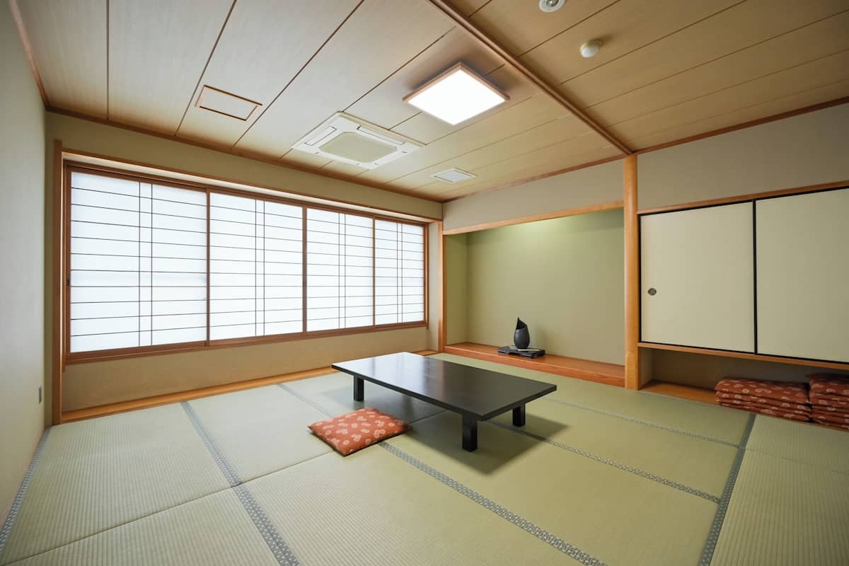 Una habitación japonesa tradicional con suelo de tatami, una mesa baja, puertas correderas y un armario.