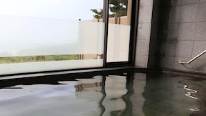 Suelo mojado en una habitación moderna con un separador de vidrio, una barandilla metálica y vistas al exterior con vegetación.