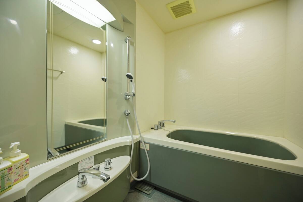 Un baño con bañera, lavamanos, espejo y ducha.