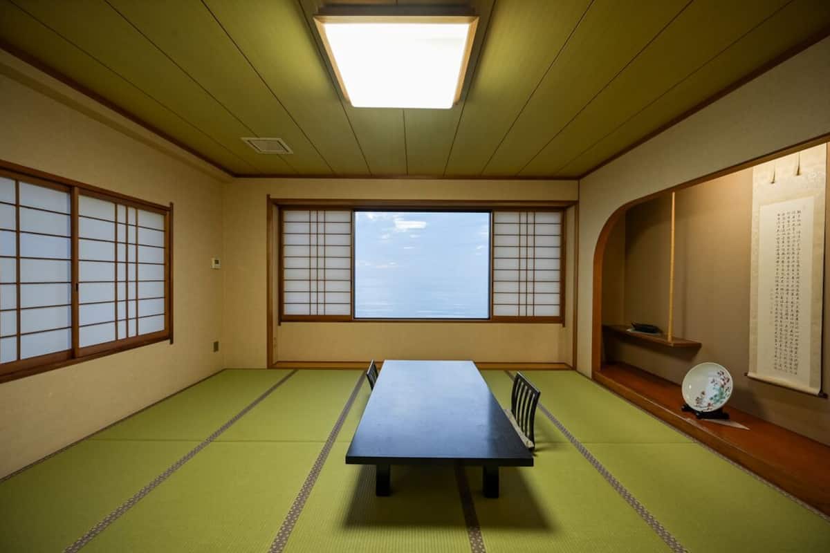 Una habitación con esteras de tatami, una mesa baja, paneles shoji y vista al cielo.