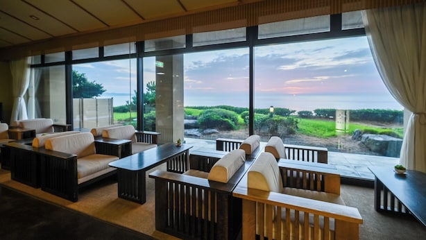 Un moderno vestíbulo de hotel con amplios ventanales, zonas de estar y vistas al paisaje.