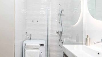 A modern bathroom with a glass shower enclosure, a built-in toilet, and a vanity with a mirror.