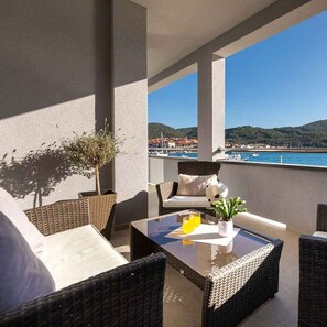 Ein Balkon mit Korbmöbeln, einem Glastisch und einem Blumentopf.