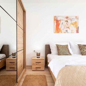 Ein Schlafzimmer mit einem Bett, einem Nachttisch mit Lampe, einem Holzschrank und einem Bild an der Wand.
