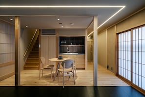 A modern interior with a wooden staircase, a kitchen area, and a dining space. - Anjin Gosho Ebisugawa (Kyoto)