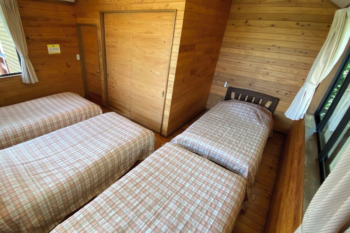 Eine Holzhütte mit zwei Betten, einem Fenster und einer Tür.
