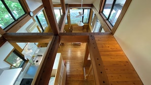 Ein Zimmer mit hohen Decken und Holzbalken, einer Küchenzeile mit Spüle und Arbeitsplatte sowie großen Fenstern mit Blick ins Grüne.