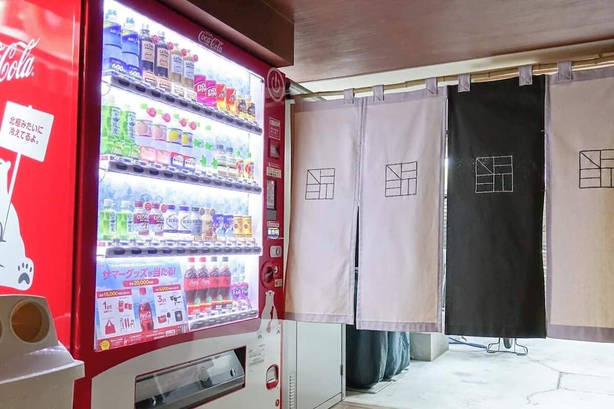 Een automaat met verschillende drankjes, een Coca-Cola logo, een afbeelding van een ijsbeer en een bord met Japanse tekst.