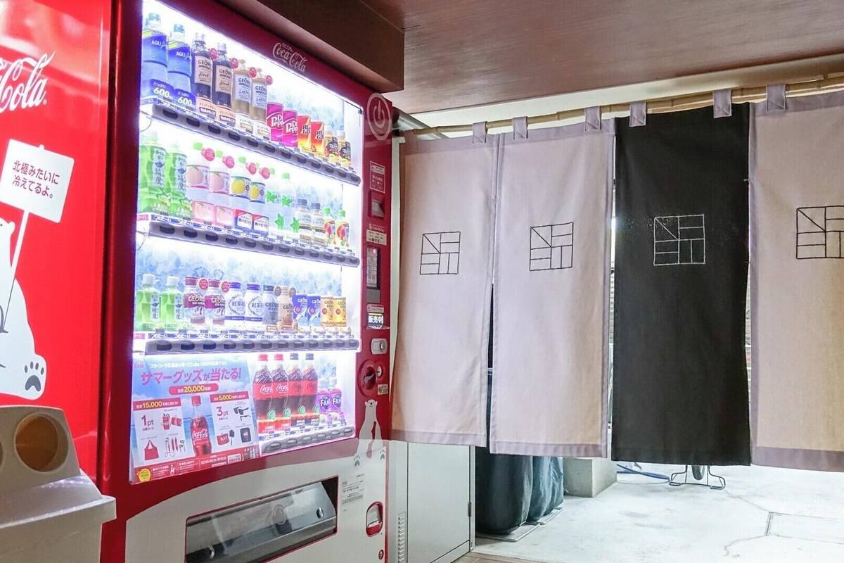 A vending machine with various drinks and a Coca-Cola logo, a polar bear illustration, and a sign in Japanese.