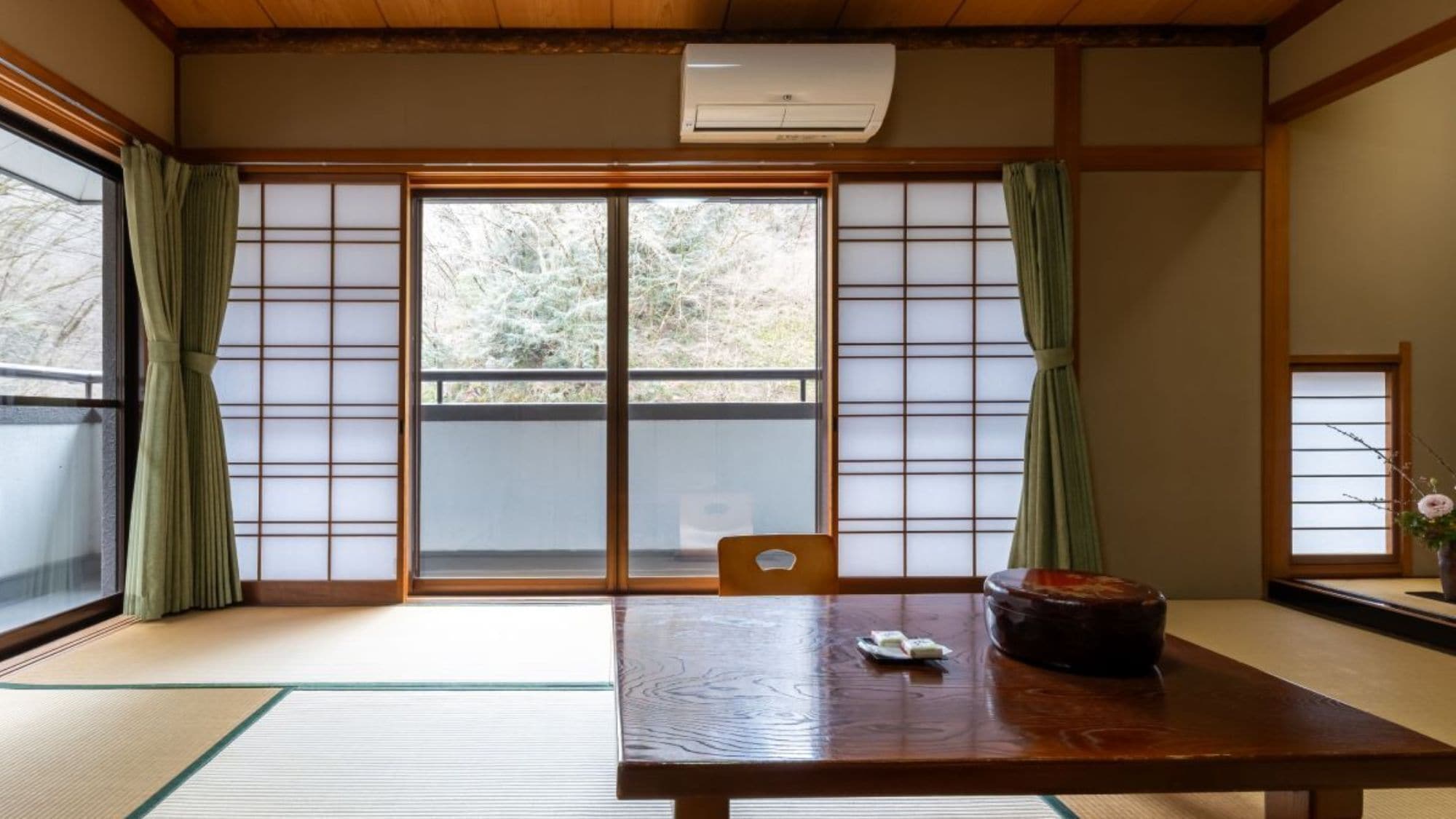 A traditional Japanese room with tatami flooring, sliding doors, a wooden table, and a small table lamp.