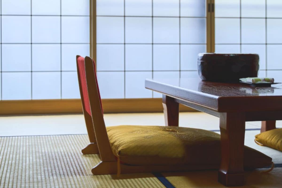 Una habitación japonesa tradicional con suelo de tatami, una mesa baja y una silla de madera.