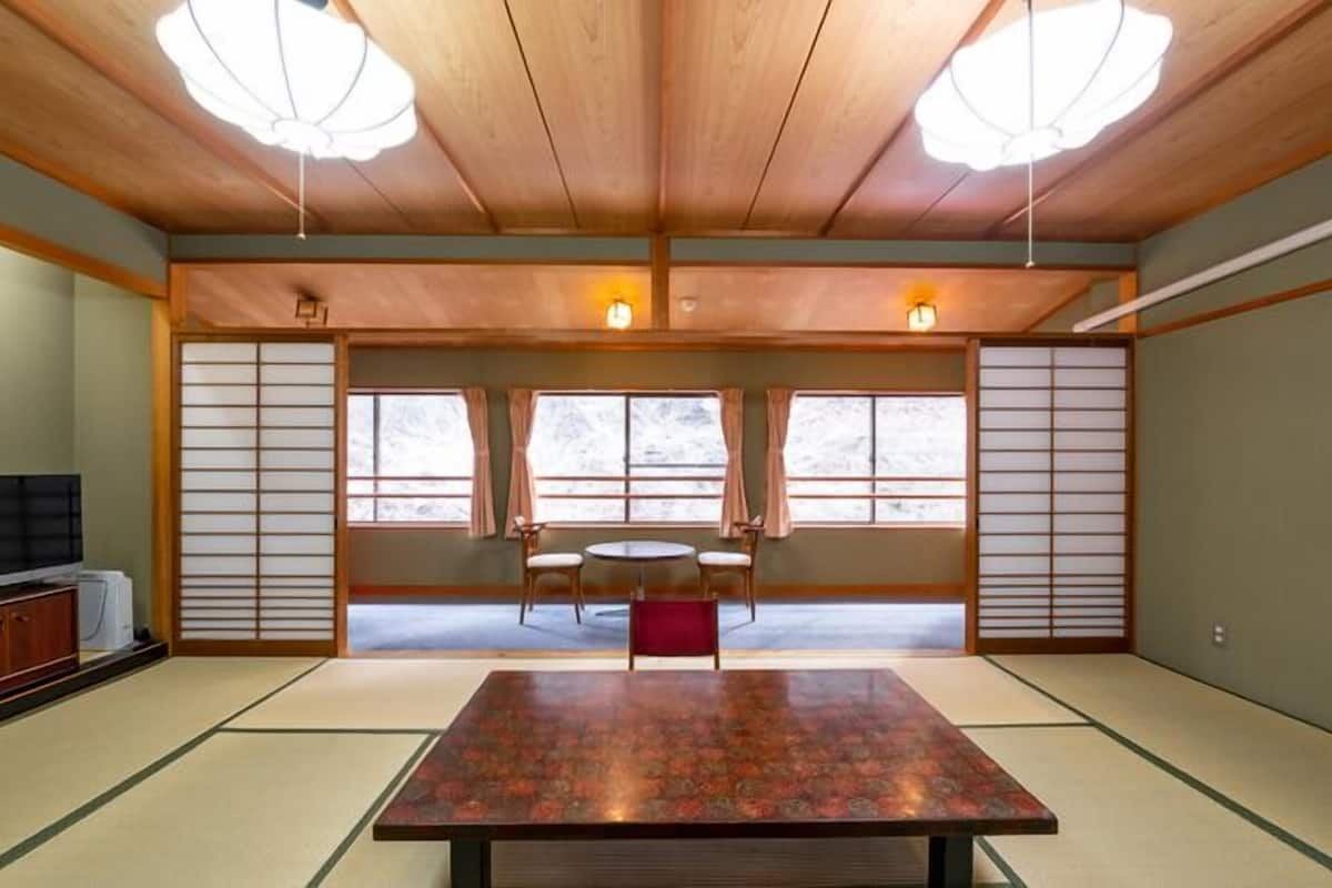 A traditional Japanese room with tatami flooring, a low table, two chairs, and sliding doors.