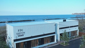 Ein modernes Gebäude mit flachem Dach, großen Fenstern und Blick auf den Ozean.