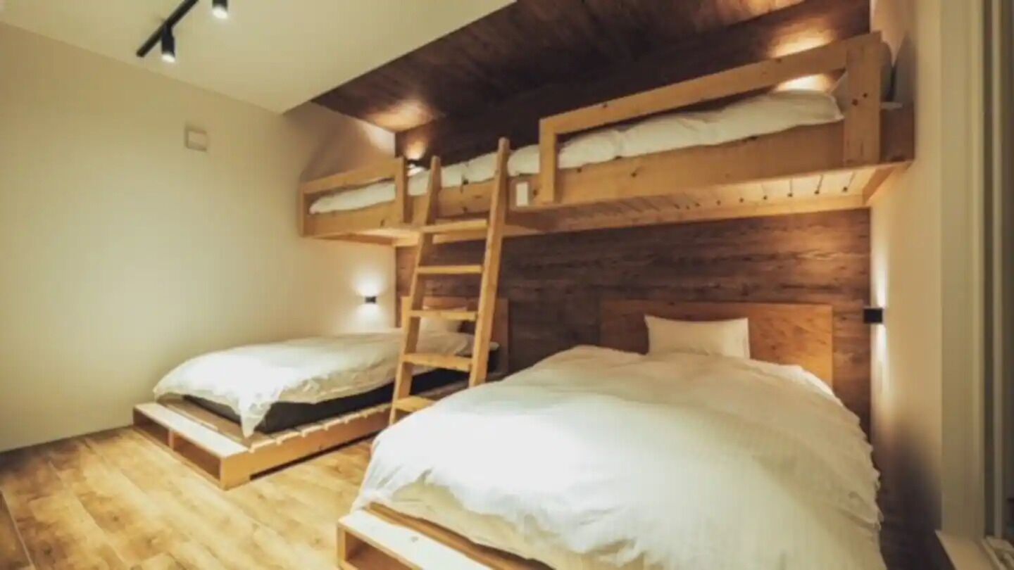 Una habitación con literas, paredes de madera y una escalera.