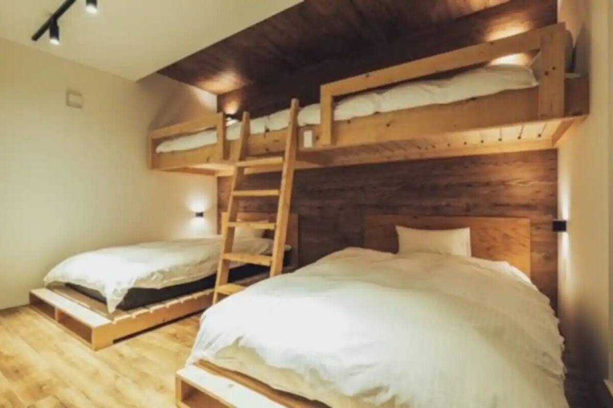 Una habitación con literas, paredes de madera y una escalera.