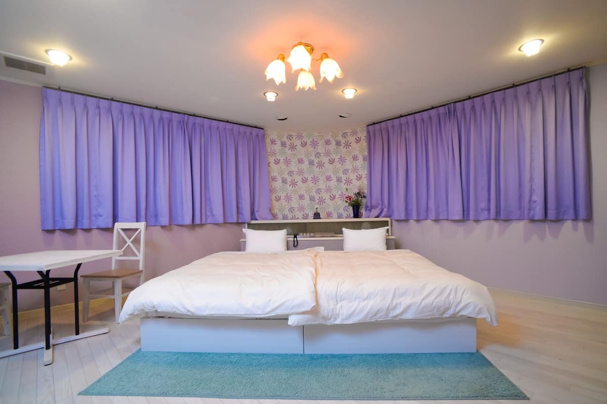 A bedroom with a bed, a desk, and a chair.