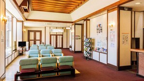 A hotel lobby with seating, a television, a reception desk, and informational posters on the walls. - Lupia Inn Nanko (Suwa)