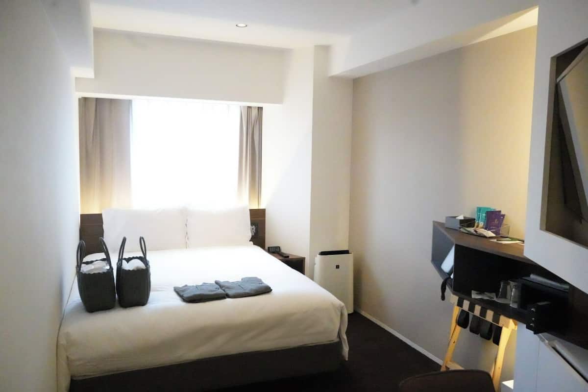 Une chambre d’hôtel avec un lit, un bureau équipé d’un ordinateur et une télévision.