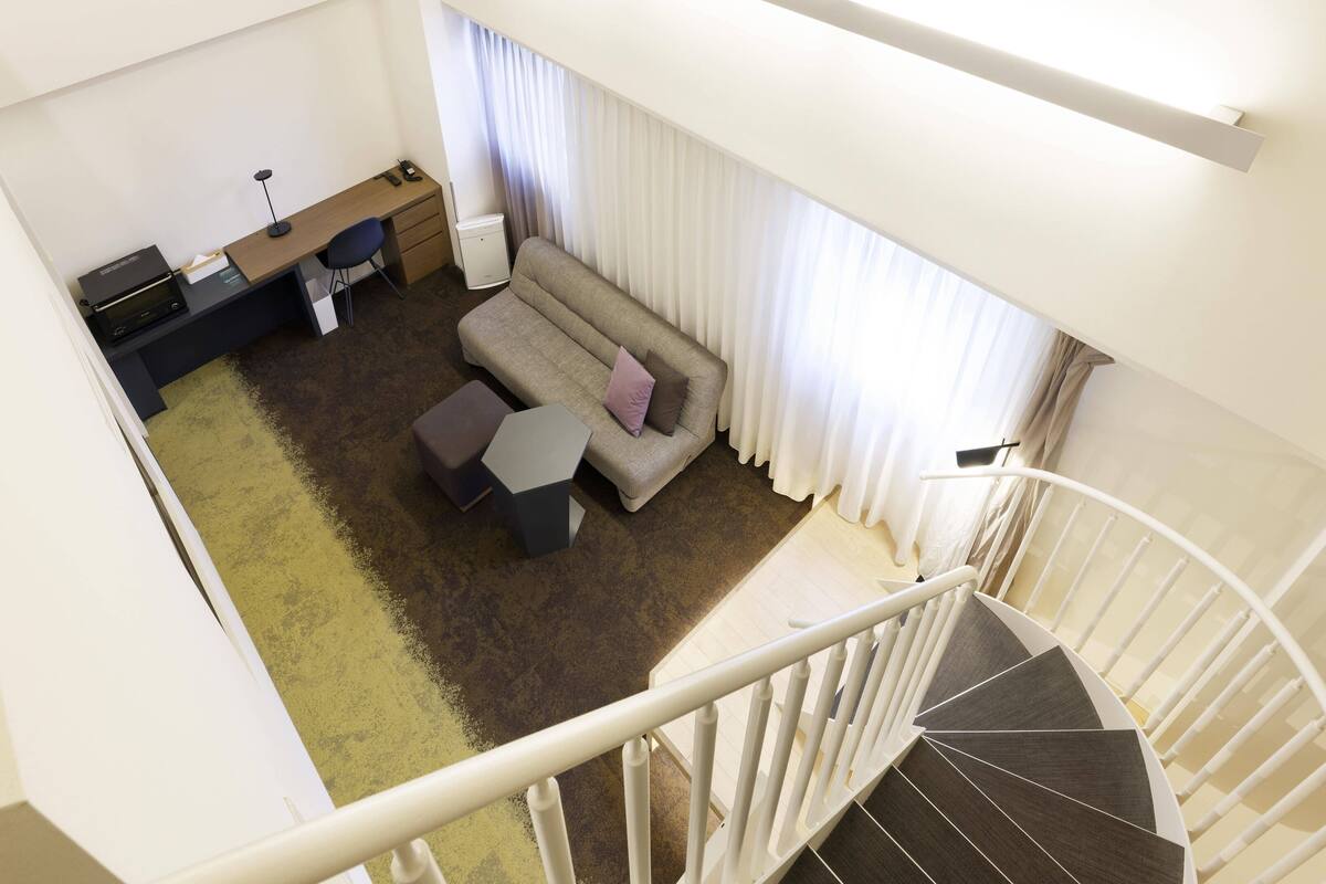 Un intérieur moderne avec un canapé, un bureau et un escalier.