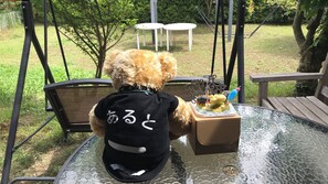 Un perro con una camiseta negra con letras blancas, sentado a una mesa de vidrio con un plato de comida.