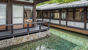 Un edificio de estilo japonés tradicional con un porche de madera y una fuente con revestimiento de piedra.