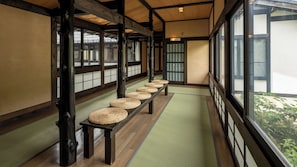 Une pièce de style japonais traditionnel, avec un sol recouvert de tatamis, un banc en bois agrémenté de nattes tissées et des portes coulissantes.