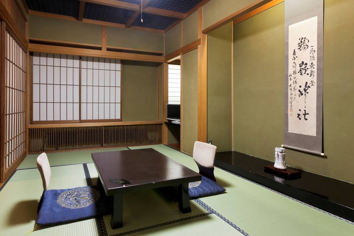 Una habitación japonesa tradicional con suelo de tatami, una mesa baja y un televisor.
