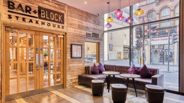 A bar and block steakhouse interior with wooden walls, large windows, and seating areas. - Premier Inn Glasgow City Centre Hotel (Glasgow)