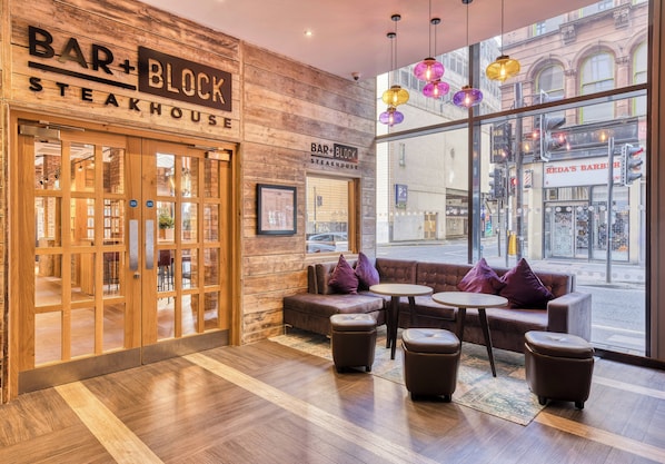 A bar and block steakhouse interior with wooden walls, large windows, and seating areas.