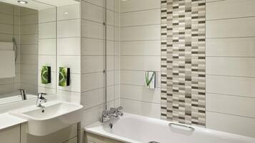 Un baño moderno con lavamanos doble, bañera y ducha.