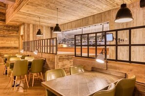 A restaurant with wooden walls, a long counter, and several tables with chairs.