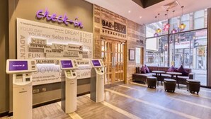 A hotel lobby with a check-in counter, a seating area, and a view of the street. - Premier Inn Glasgow City Centre Hotel (Glasgow)