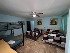Una habitación con literas, ventilador de techo y obras de arte en las paredes.