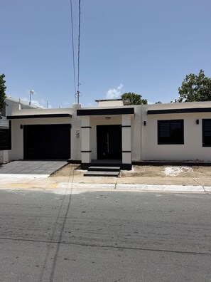 Un edificio de dos pisos con un garaje en la planta baja y una puerta principal con escalones de acceso.