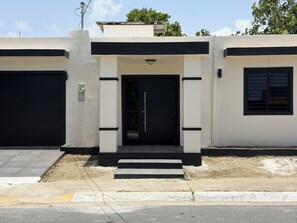 Un edificio moderno con una puerta negra, un garaje y un ventanal pequeño.