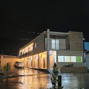 A two-story building with a covered entrance and a car parked in front.