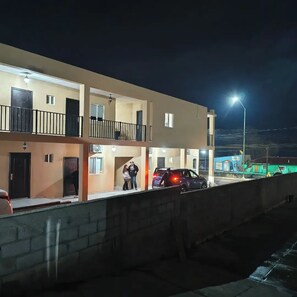 A multi-story building with balconies, a parking area, and a streetlight. - Hotel Mukí Galá  (Creel)