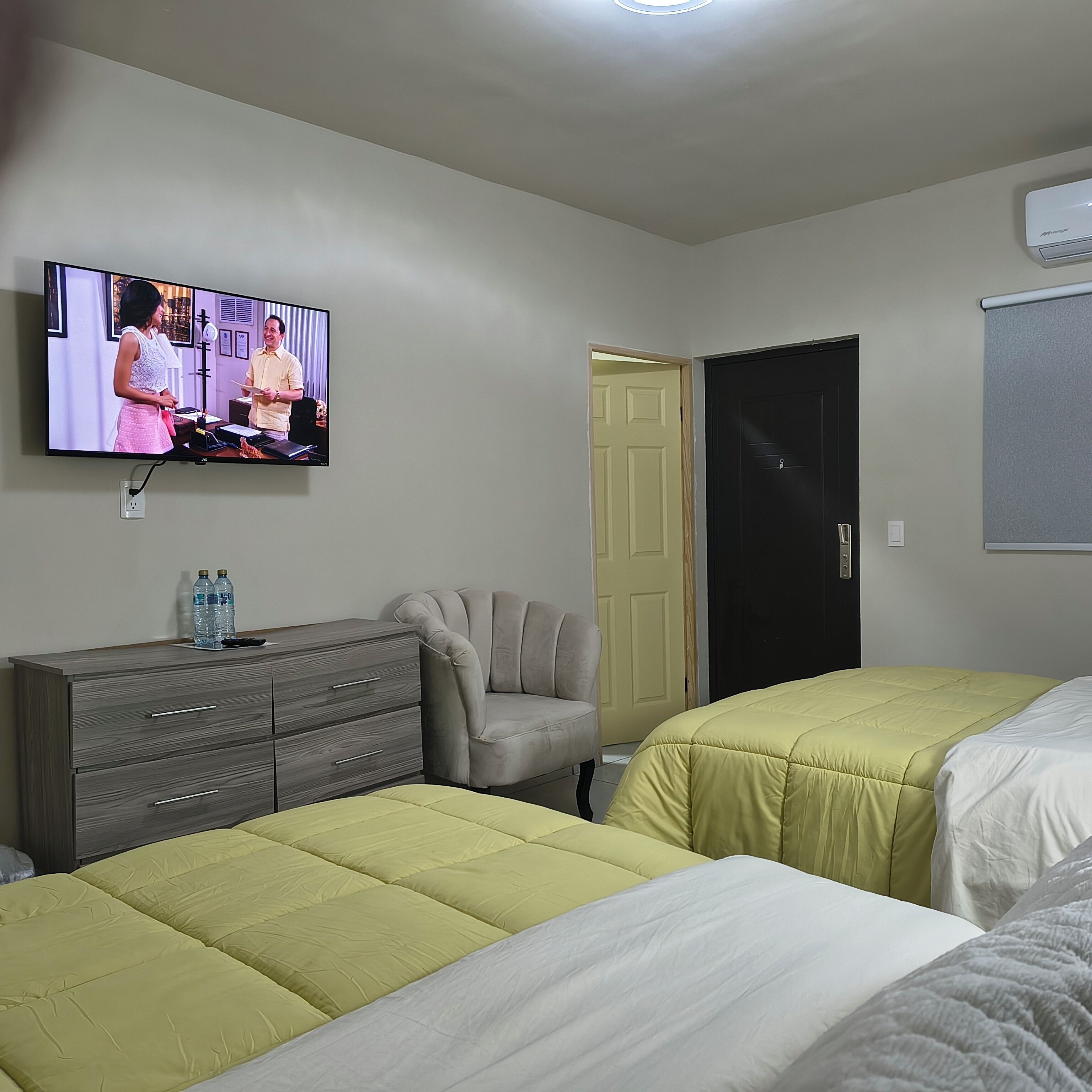 Een hotelkamer met twee bedden, een televisie, een dressoir en een deur.